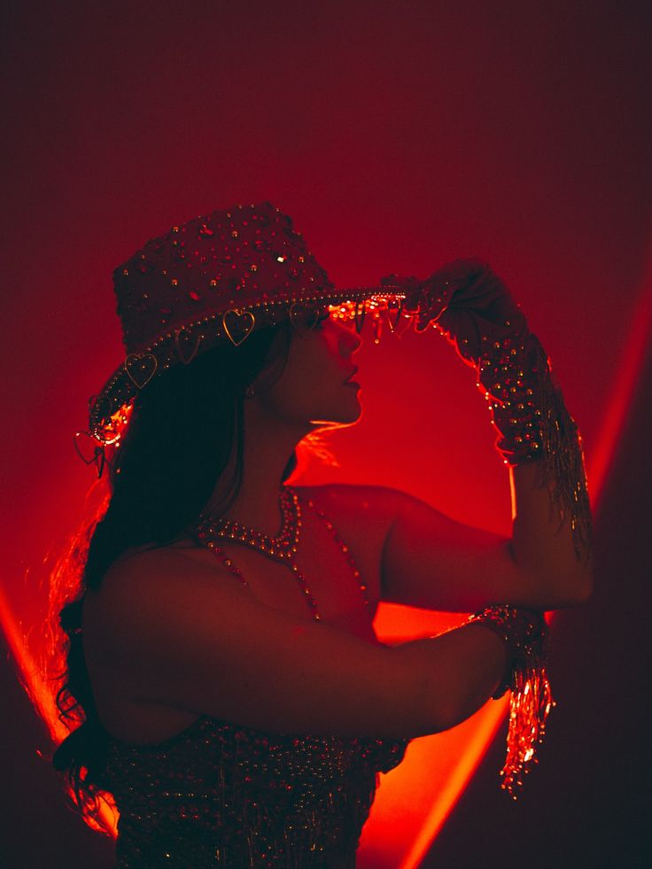 Kırmızı neon ışıkta taşlı şapkalı sahne performansı
